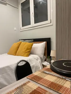 a bedroom with a bed and a table with a yellow pillow at Aiolos apartment alimos centre 4 near the sea in Athens