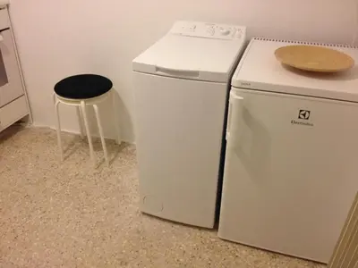 a white refrigerator and a stool next to a washing machine at Studio close to Athens centre, fast internet. in Athens