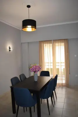 a dining room table with blue chairs and a vase with flowers at Cozy Project Kaisariani in Athens