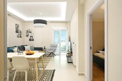 a living room and dining room with a white table and chairs at Jade Residence - Greecing in Athens
