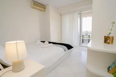 a white bedroom with a bed and a window at Blue vibes by Glyfada beach in Athens