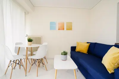 a living room with a blue couch and a table at Blue vibes by Glyfada beach in Athens