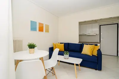 a living room with a blue couch and a table at Blue vibes by Glyfada beach in Athens