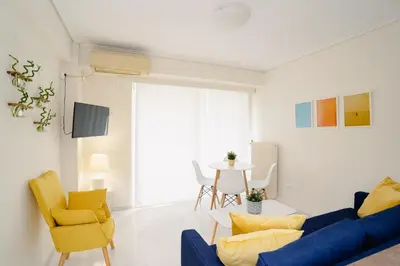 a living room with a blue couch and yellow chairs at Blue vibes by Glyfada beach in Athens