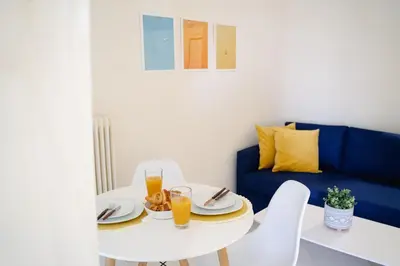 a dining room with a white table and a blue couch at Blue vibes by Glyfada beach in Athens