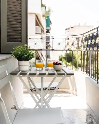 a table on a balcony with two glasses of orange juice at Ranny House in Athens