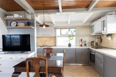 a kitchen with white cabinets and a table and a tv at Sunny Loft with a Panoramic View in Athens