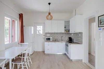 a kitchen with white cabinets and a table and chairs at Private house - Garden - Glyfada in Athens