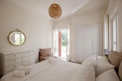 a white bedroom with a large bed and a mirror at Private house - Garden - Glyfada in Athens