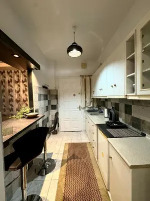 a kitchen with white cabinets and a table and chairs at Cozy home in Nea Smirni in Athens