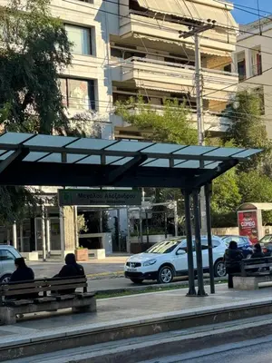 two people sitting on benches at a bus stop at Cozy home in Nea Smirni in Athens