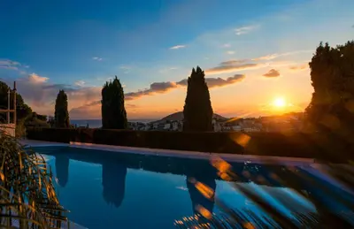 a sunset over a swimming pool with trees at Luxurious Family friendly Villa Anavyssos in Anavissos