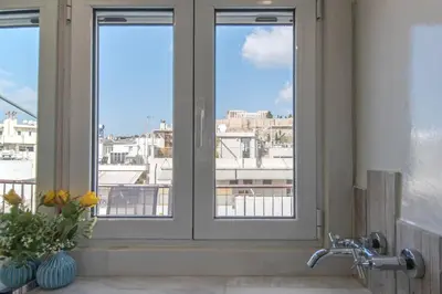 a bathroom with three windows with a view of a city at Parthenon crown penthouse in Athens