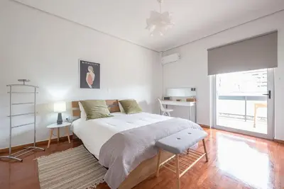 a white bedroom with a large bed and a desk at Open -view Apartment, YGEIA Hospital in Athens