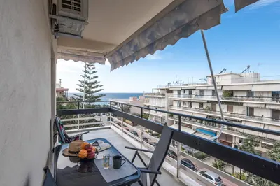 a balcony with a table and chairs and a view of the ocean at Valeria's Sea View Apartment in Athens