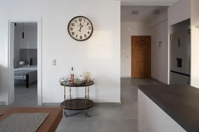 a room with a clock on the wall and a table at Valeria's Sea View Apartment in Athens