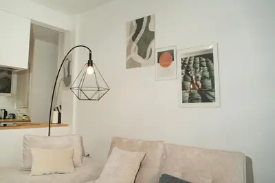 a white living room with a couch and a lamp at E44 by SpitiSou in Athens