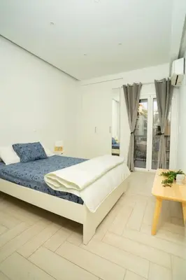 a white bedroom with a bed and a table at E9 by SpitiSou in Athens