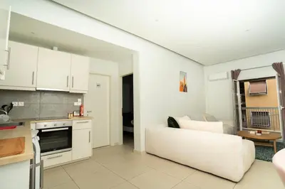a living room with a white couch and a kitchen at E9 by SpitiSou in Athens