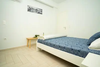 a white bedroom with a bed and a table at E9 by SpitiSou in Athens