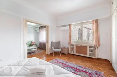 a bedroom with a bed and a chair and a window at Athenian Gate Residence to Plaka in Athens
