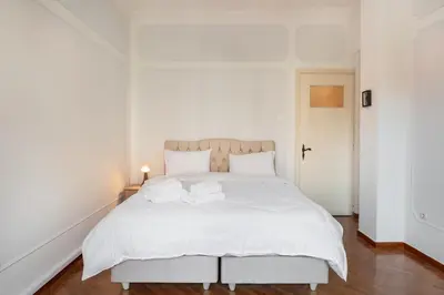 a white bedroom with a large white bed with two towels at Athenian Gate Residence to Plaka in Athens
