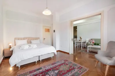 a white bedroom with a bed and a living room at Athenian Gate Residence to Plaka in Athens