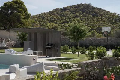a backyard with a barbecue with a mountain in the background at Villa Vel Aegina in Vaia