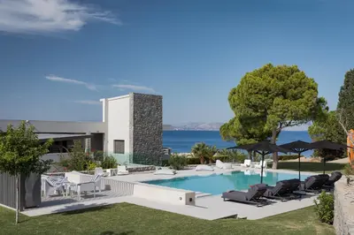 a house with a swimming pool with chairs and umbrellas at Villa Vel Aegina in Vaia