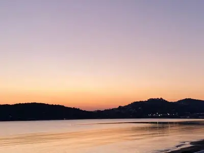 a sunset over a body of water with mountains at Villa Infinity View Athens Riviera in Anavissos