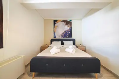 a bedroom with a bed with a painting on the wall at Villa Infinity View Athens Riviera in Anavissos