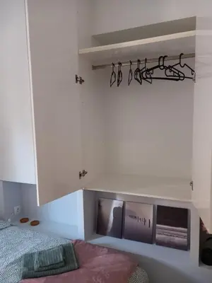 a bedroom with white cabinets and a tv on the wall at Leo Athens Apartment Near Tram Station in Athens