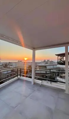 a view of the sunset from the balcony of a building at Luxury Penthouse w/ sea view in Athens
