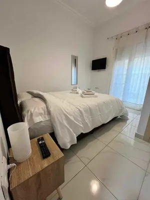a white bedroom with a bed and a television at Elegant & Modern Apartment near to Athens Riviera in Piraeus