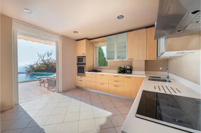 a kitchen with wooden cabinets and a view of the ocean at Serenity Villa by Comfortbnb in Saronida