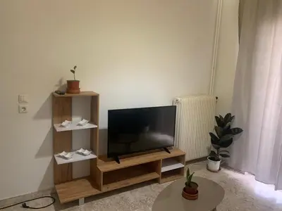 a flat screen tv sitting on a wooden stand in a living room at Calma apartment in Athens