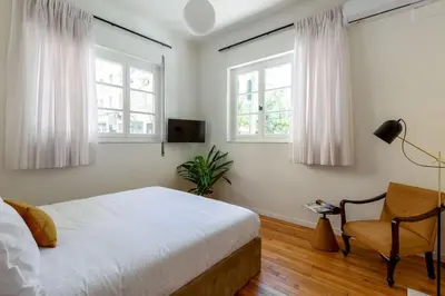 a bedroom with a bed and a chair and windows at The Met by Zoia Living in Athens