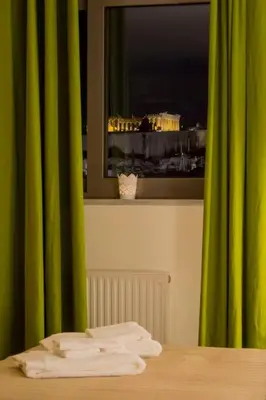 a room with a table with a window with green curtains at Front-Row Acropolis View Balcony - Central Athens in Athens