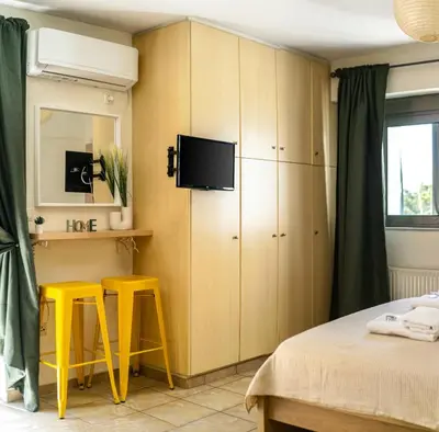 a bedroom with two yellow stools and a tv at Front-Row Acropolis View Balcony - Central Athens in Athens