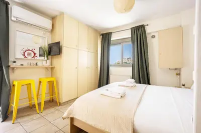a bedroom with a bed and two yellow stools at Front-Row Acropolis View Balcony - Central Athens in Athens