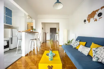 a living room with a blue couch and a yellow table at Stunning Acropolis View from a Sunny Renovated Apartment in Athens