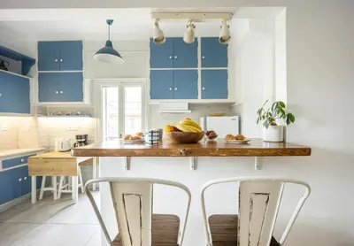 a kitchen with blue cabinets and bar stools at Stunning Acropolis View from a Sunny Renovated Apartment in Athens