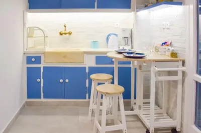 a small kitchen with blue cabinets and stools at Stunning Acropolis View from a Sunny Renovated Apartment in Athens