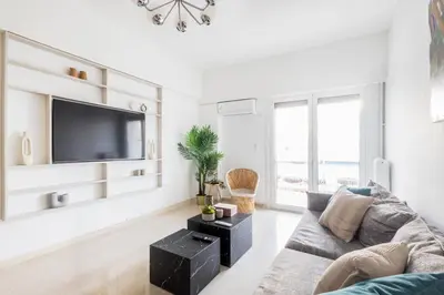 a living room with a couch and a flat screen tv at Sunny n Luxury apt in Glyfadas center in Athens