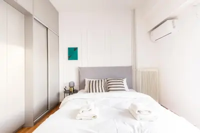a white bedroom with a large bed with towels on it at Sunny n Luxury apt in Glyfadas center in Athens