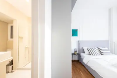 a white bedroom with a bed and a bathroom at Sunny n Luxury apt in Glyfadas center in Athens