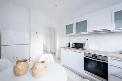a kitchen with white appliances and a table with two baskets at Sunny n Luxury apt in Glyfadas center in Athens