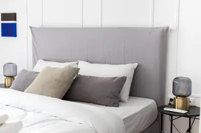 a bed with white sheets and gray pillows at Sunny n Luxury apt in Glyfadas center in Athens