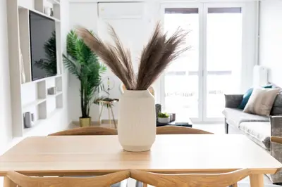 a white vase with feathers on a table in a living room at Sunny n Luxury apt in Glyfadas center in Athens