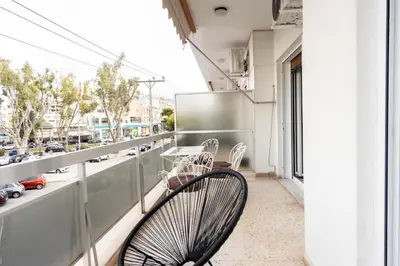a chair on a balcony with a view of a street at Sunny n Luxury apt in Glyfadas center in Athens